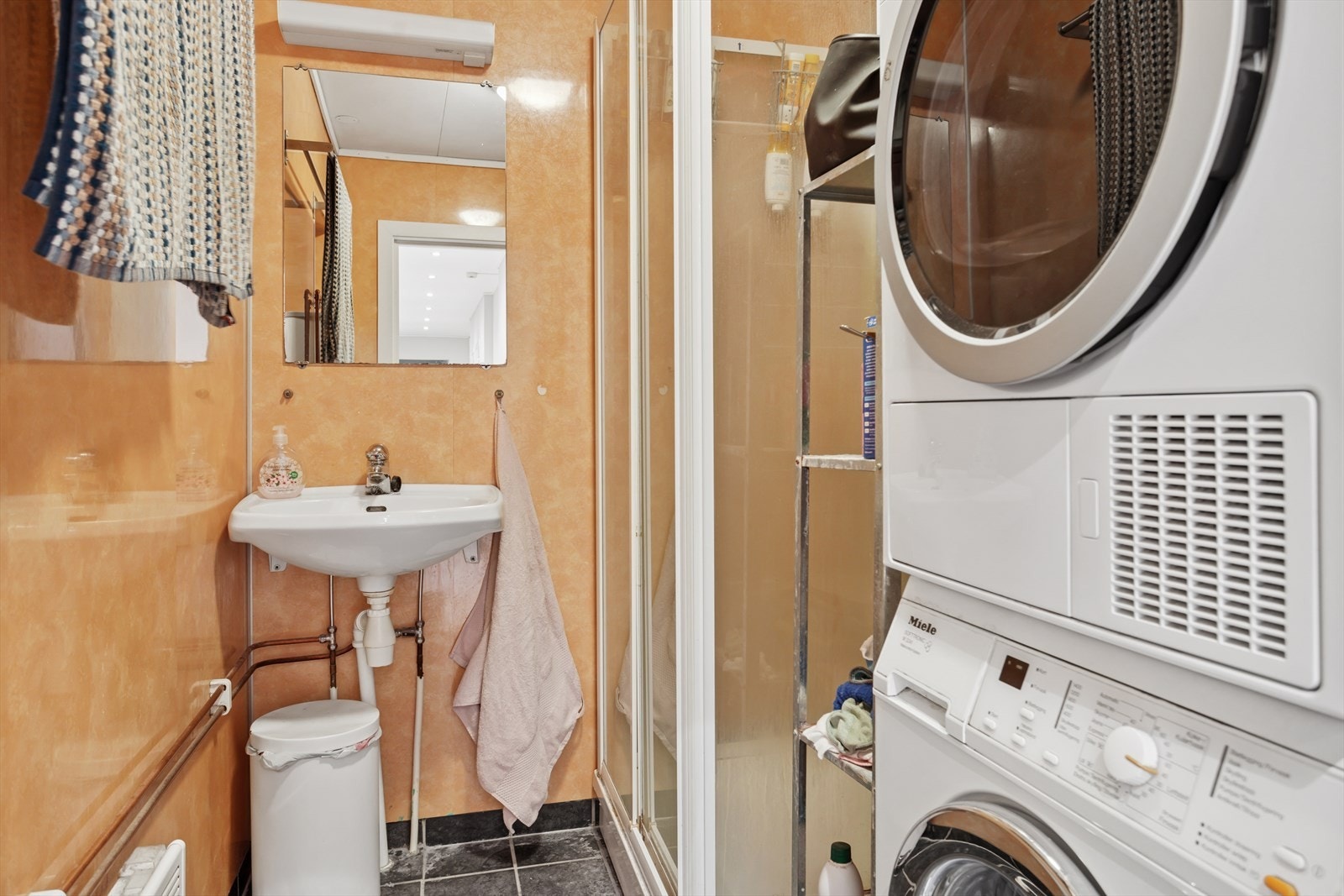 Baderommet har flis på gulv med elektriske varmekabler og våtromsplater på vegger. Takess i himling. Utstyrt med servant, mekanisk avtrekk, opplegg for vaskemaskin og dusjkabinett Galleribilde