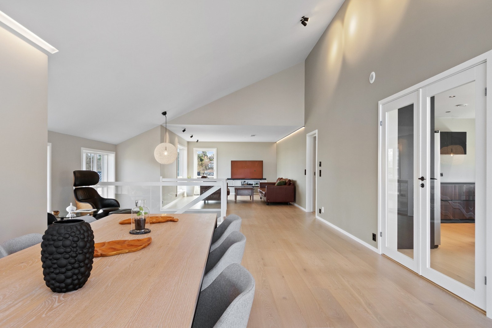 De store vinduene gir fint utsyn til det grønne nærmiljøet, og på kvelden får man følelsen av å ha solnedgangen rett inn i spisestuen. Galleribilde