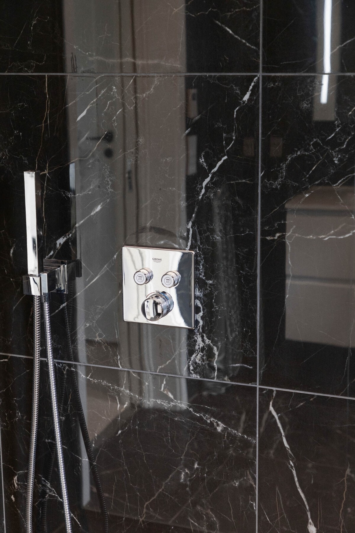 Dette badet har vegger og gulv belagt med sorte, marmorerte fliser og har et smalt vindu med flissatt karm. Galleribilde