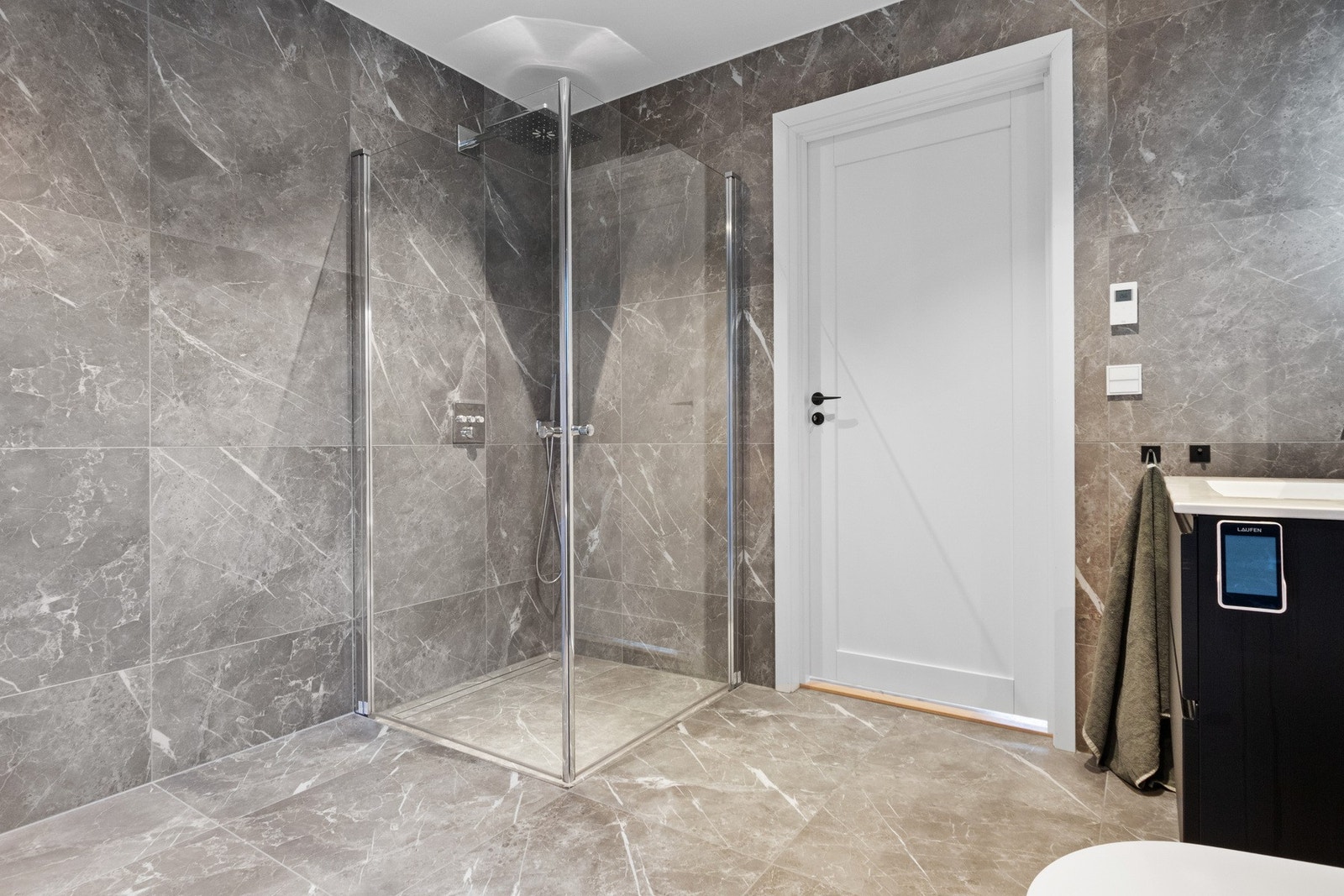 Dusjhjørnet har regnfallsdusj. Innredningen består av en heldekkende servant på sort skuffeseksjon og wc med spylefuksjon. Galleribilde