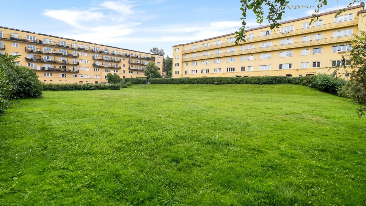 Det er store, flotte grøntarealer på begge sider av boligblokken - her kan man nyte lange, solfylte sommerdager. Galleribilde
