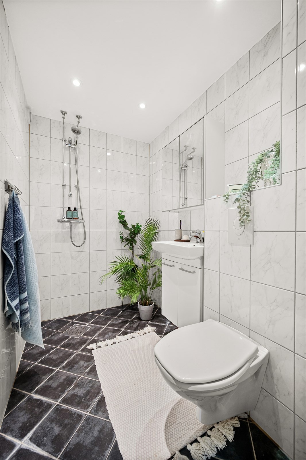 Badet har varme i gulv, opplegg for vaskemaskin, toalett, dusjnisje og servant med innredning Galleribilde