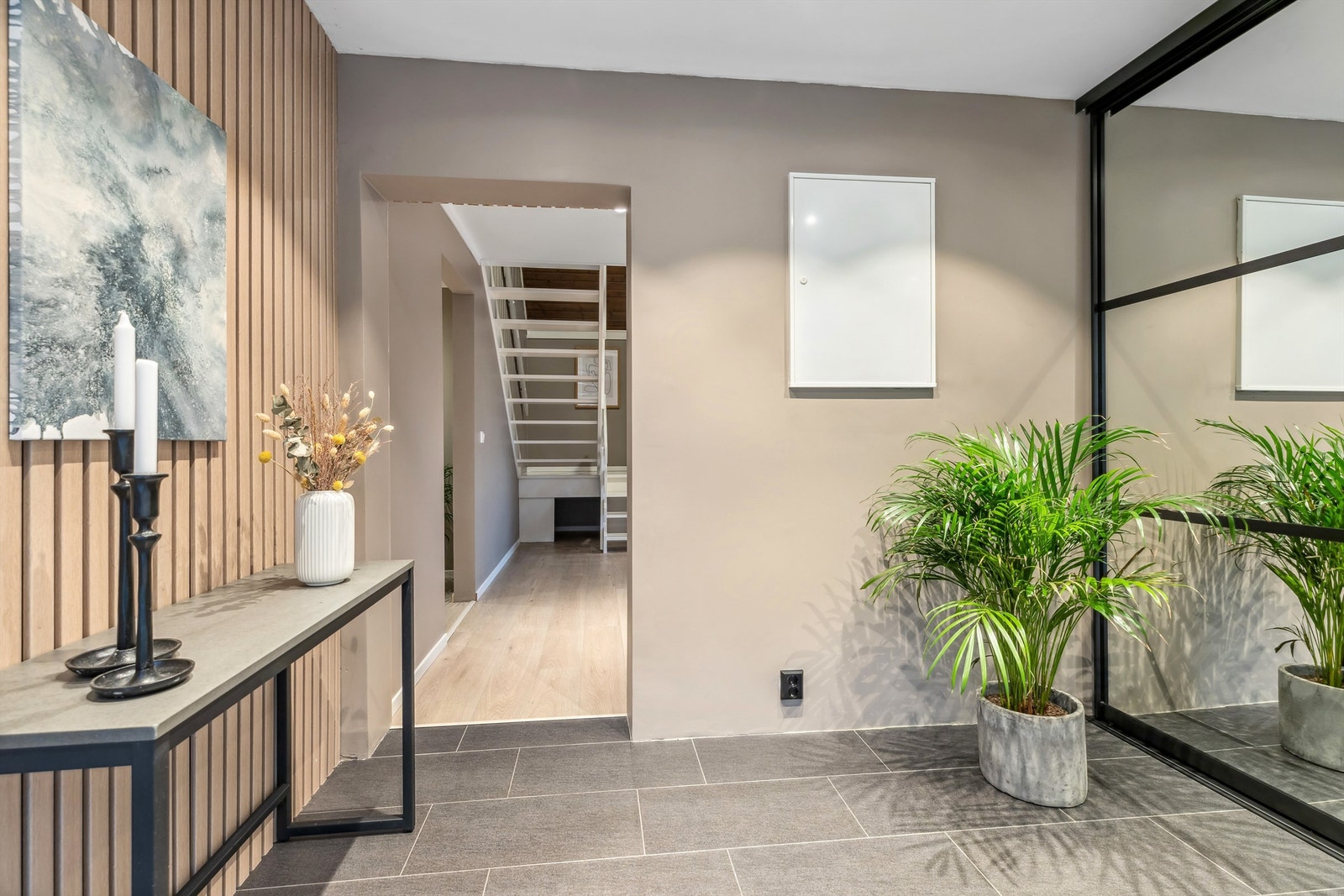 I entréen er det montert en praktisk og stor skyvedørsgarderobe med god plass til oppbevaring. Gulv lagt med fliser, og moderne spilevegg på den ene veggen Galleribilde