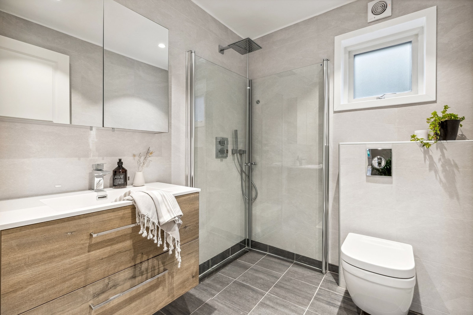 Lekkert bad fra 2019/2020 med flislagt gulv med gulvvarme, veggflater belagt med baderomsplater og malt himling med downlights Galleribilde