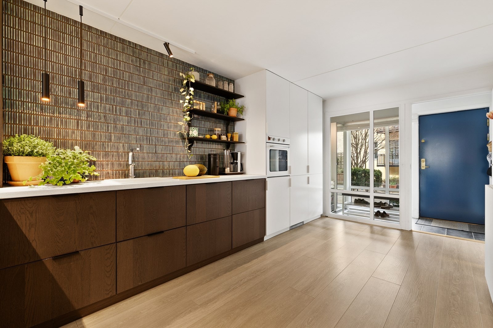 Kjøkkenet har et stilig uttrykk med fronter i to forskjellige farger, integrerte hvitevarer og ulike former for belysning. Galleribilde