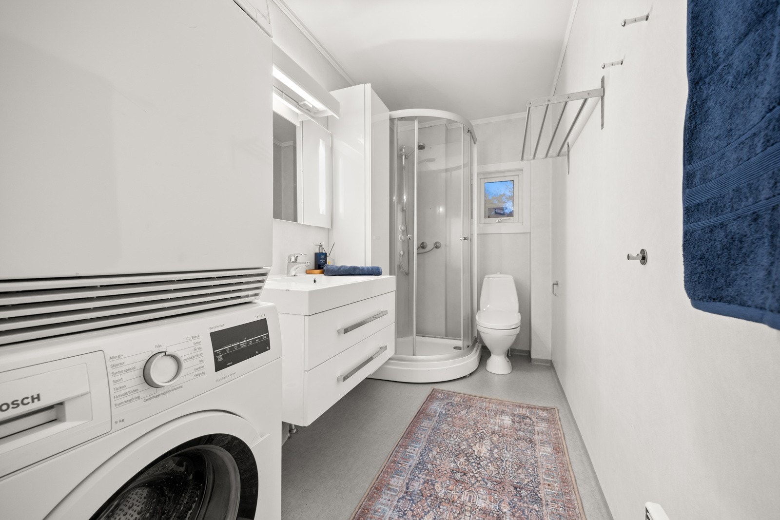 Bad med opplegg for vaskemaskin. Badet er fra byggeåret, men servant og dusjkabinett ble skiftet i 2016. Veggskap ble satt opp i 2018. Galleribilde