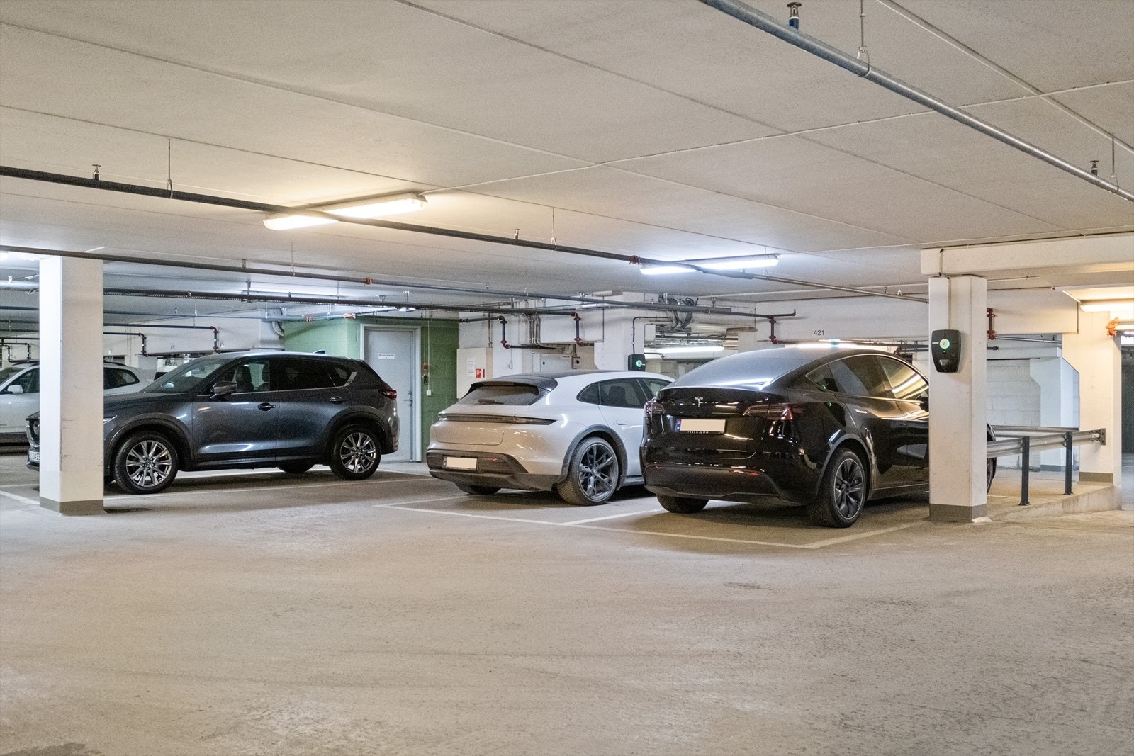 Garasjeplass medfølger i felles garasjeanlegg EL-billader. Sort Tesla står på seksjonens parkeringsplass. Galleribilde