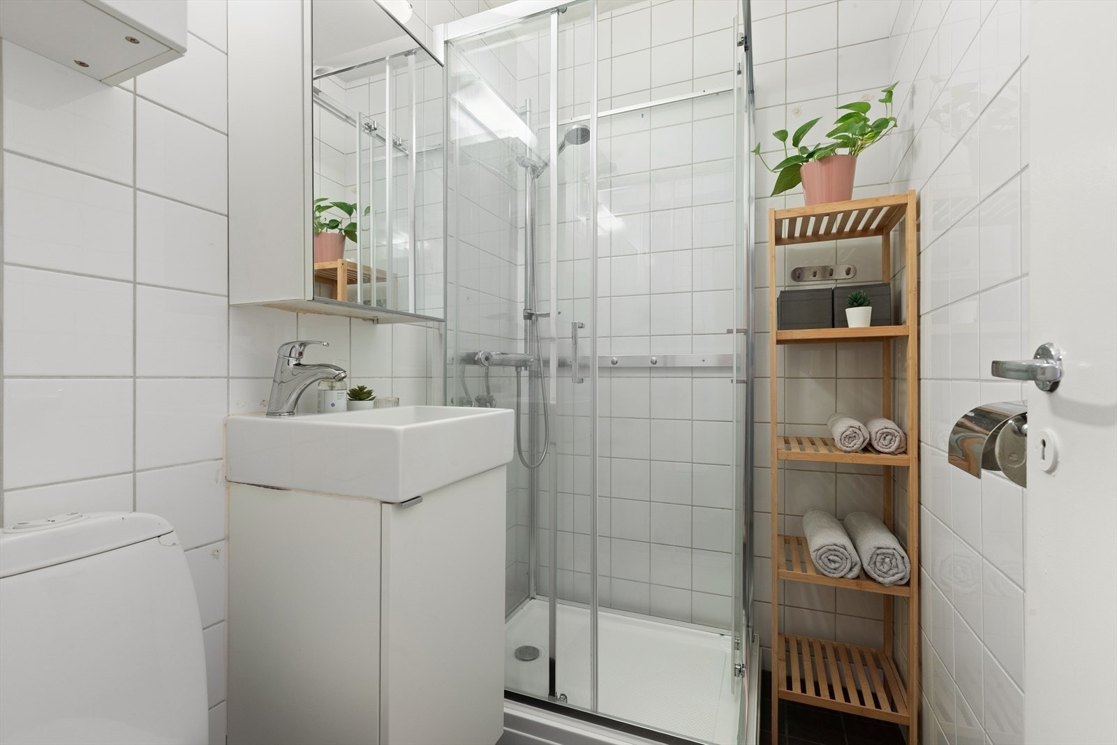 Flislagt bad med dusjkabinett, wc, servant med underskap og speilskap. Galleribilde