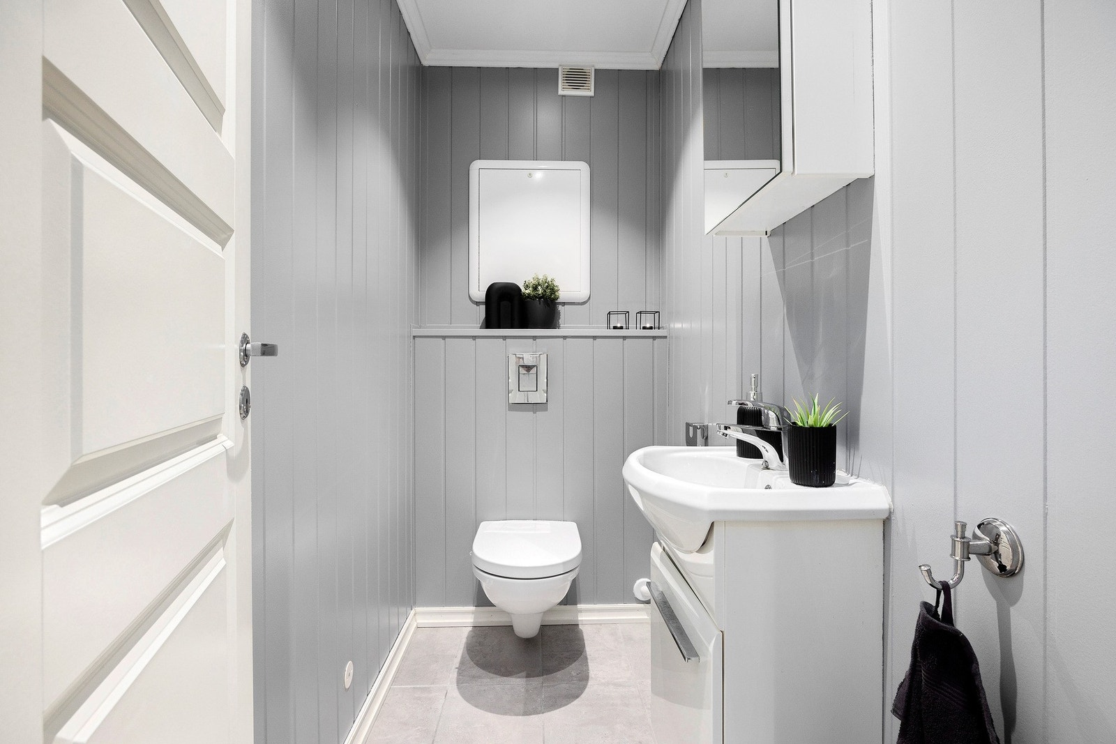 Praktisk separat toalettrom med gråmalte vegger og flislagt gulv. Galleribilde