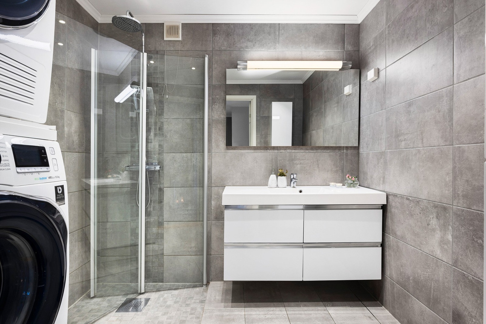 Lekkert bad fra 2016 med dokumentert utførelse og moderne flislagte overflater i grå-beige toner. Galleribilde