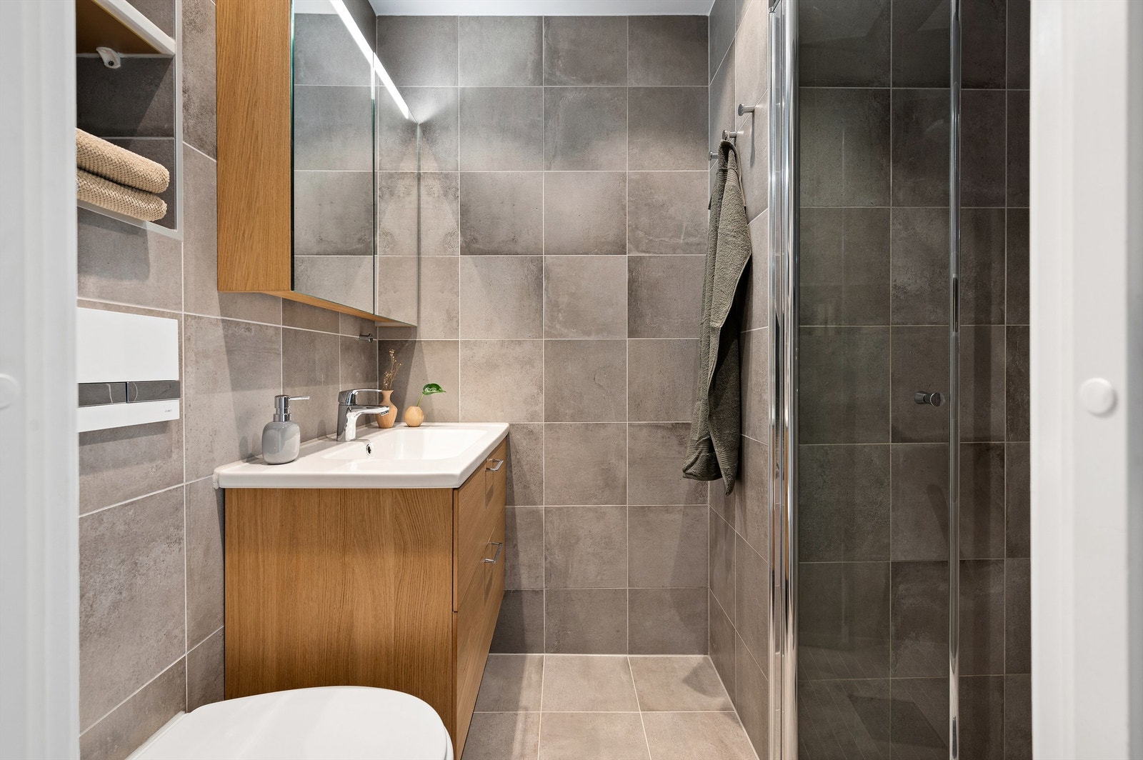 Et lekkert baderom som ble pusset opp i 2017 med flotte materialer og innredning. Overflatene er mørke og er stilfullt innredet med store, grå vegg- og gulvfliser. Badet er levert av Iconic Nordic Rooms. Varme i gulvet. Galleribilde