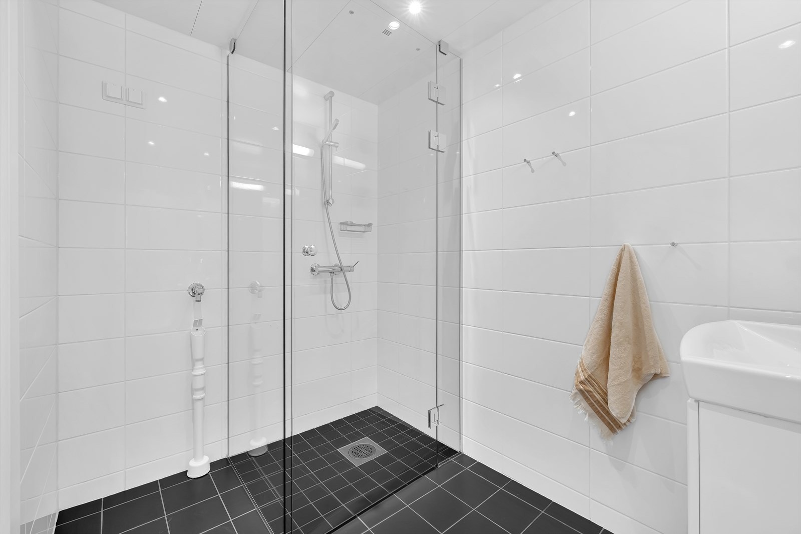 Badet er innredet med vegghengt klosett, servant nedfelt i innredning og dusjhjørne med svingbare glassdører. Det er opplegg for vaskemaskin. Galleribilde