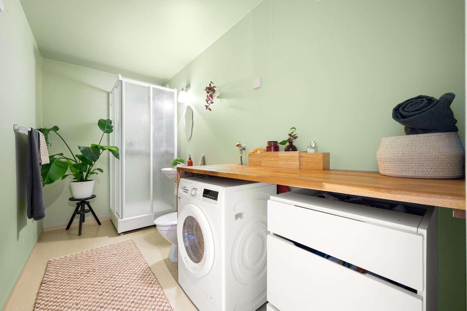 Romslig bad med opplegg for vaskemaskin. Baderommet ble malt i en frisk og delikat grønntone i april 2025. Galleribilde