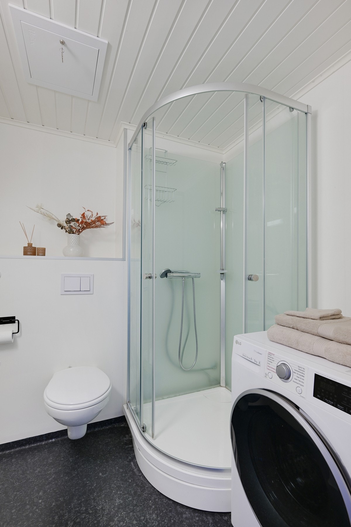 Badet er innredet med dusjkabinett, vegghengt klosett, pen baderomsinnredning og opplegg for vaskemaskin Galleribilde
