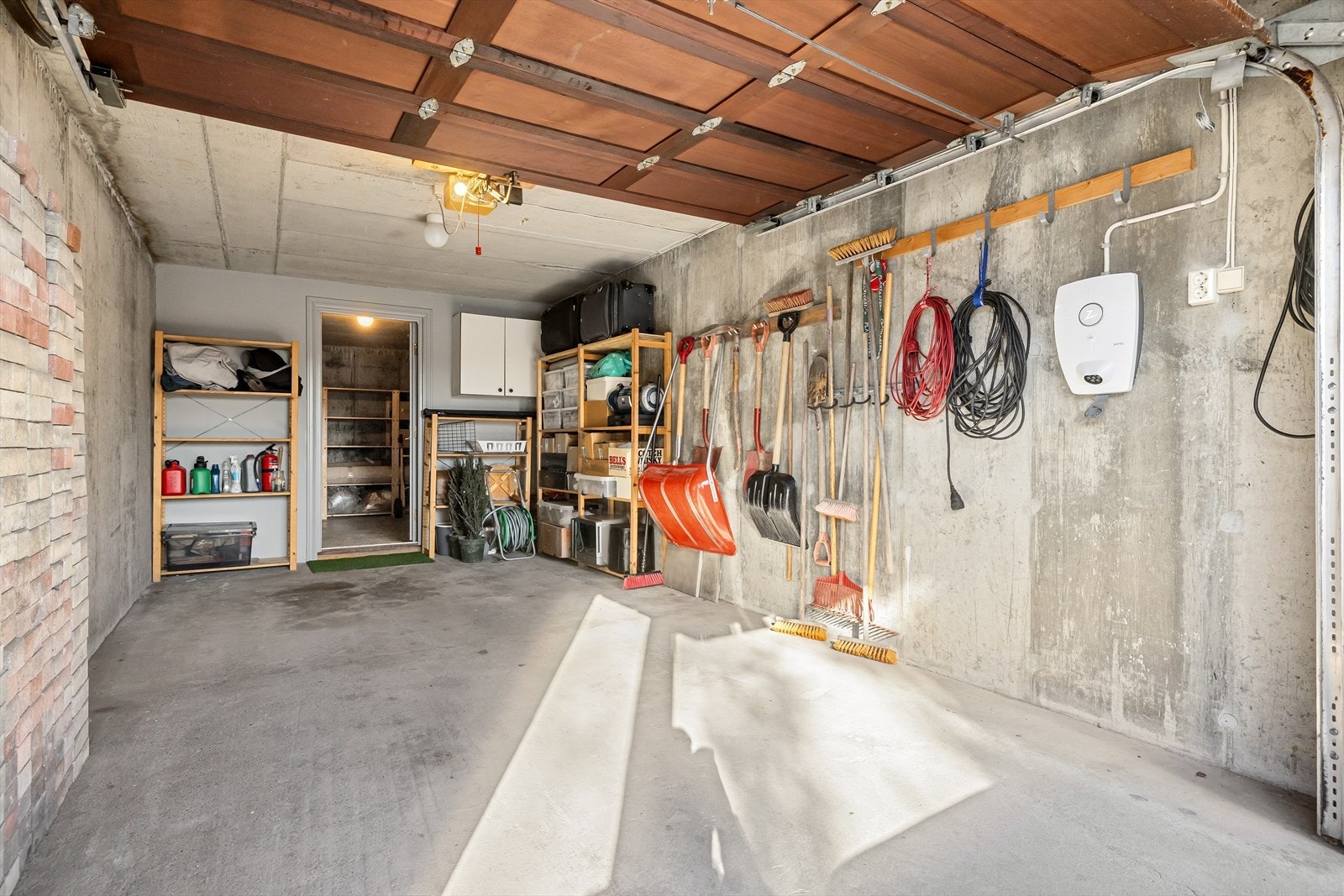 Med innvendig adkomst fra redskapsboden, kan man ta seg tørrskodd frem til garasjen med elektrisk port. Bilen kan lades enkelt via den monterte laderen på veggen i garasjen. Galleribilde