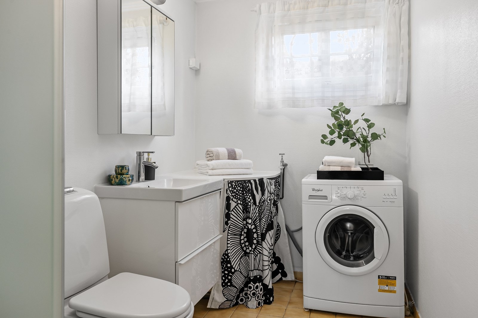 Badet har en egen varmtvannstank og er utstyrt med baderomsmøbler med nedfelt vask, overskap med speil, dusjkabinett og opplegg for vaskemaskin. Galleribilde