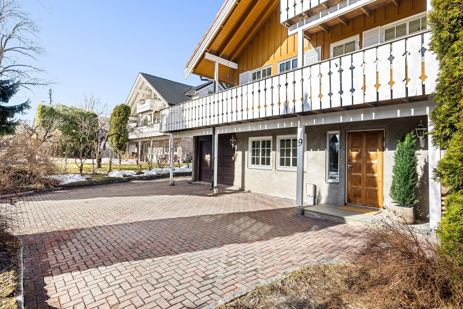 Tomten er planert over skrånende terreng, og er pent opparbeidet med plen, tujaer, busker, belegningsstein og kantstein i innkjørsel og parkeringsarealer. Galleribilde