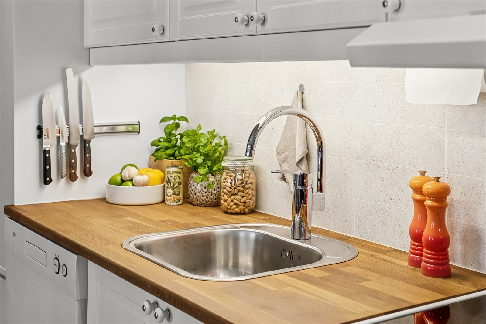 Kjøkkeninnredningen er takhøy med to overskap i høyden, og frontene er malte, profilerte og laget av MDF-materiale. Benkeplaten er av heltre eik, med laminatplater over benken. Galleribilde