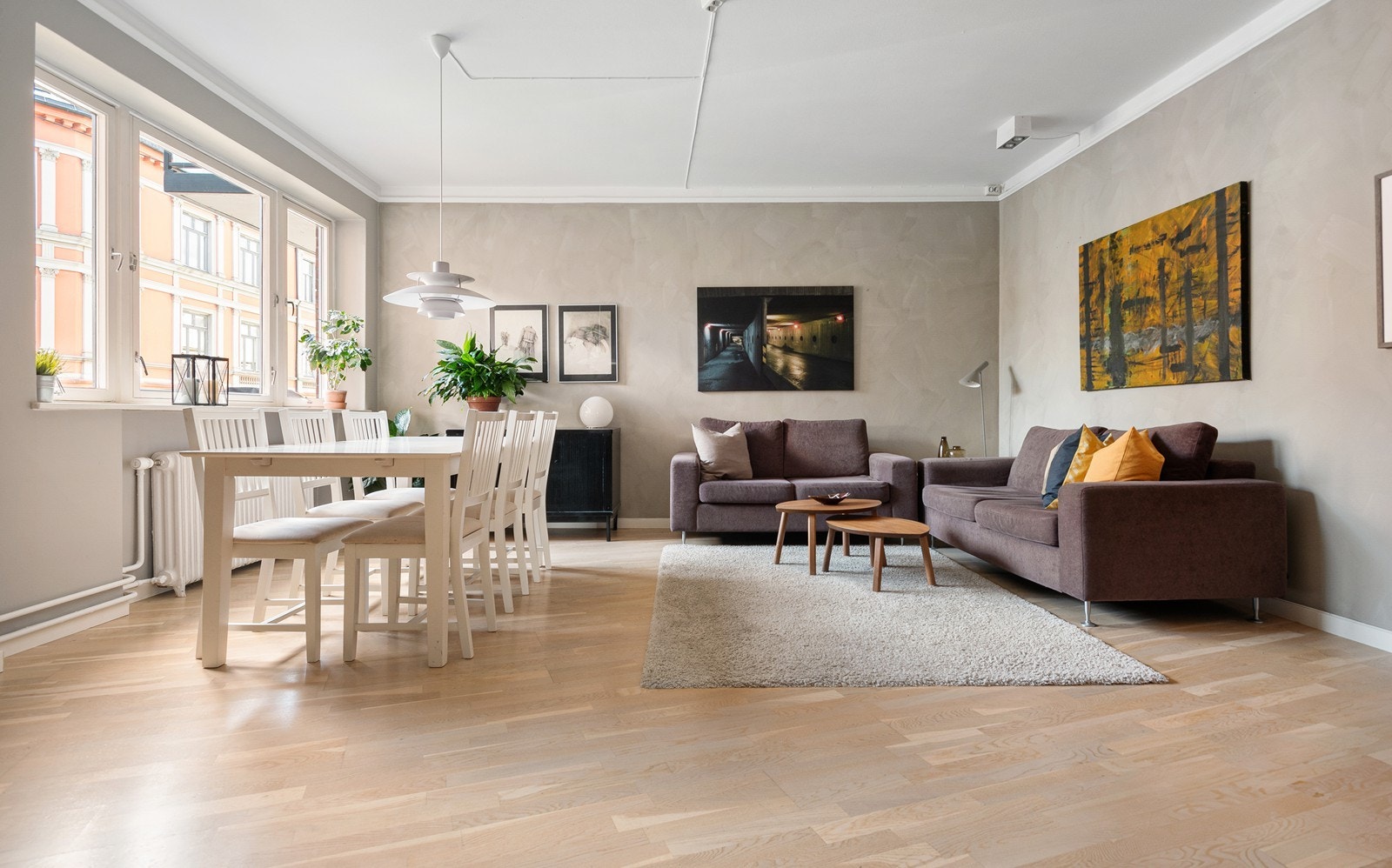 Stor og romslig stue med åpen peis og store vindusflater som slipper inn rikelig med dagslys Galleribilde