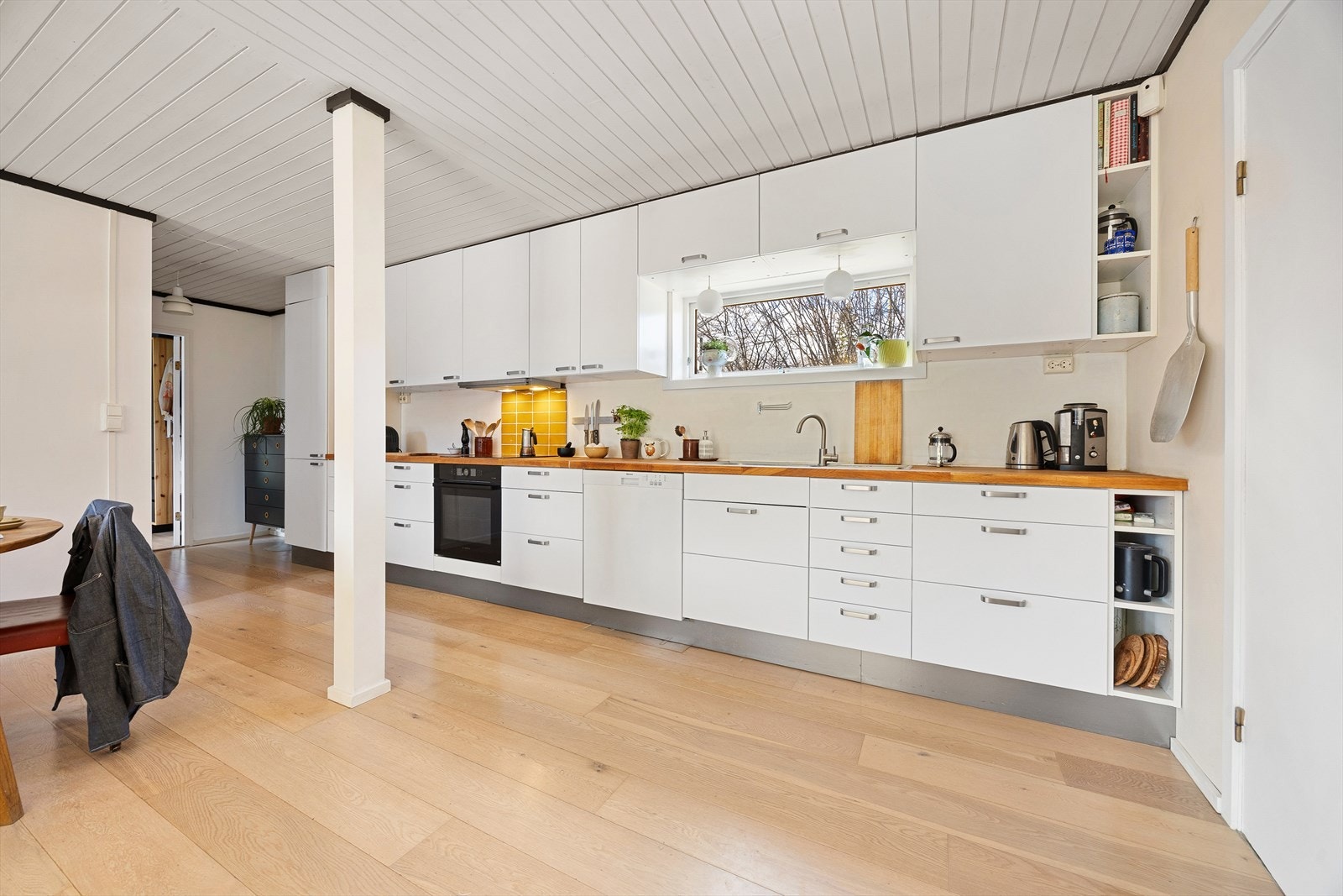 Åpen kjøkkenløsning med hvite glatte fronter og heltre benkeplate av eik. Benkeplate har blitt pusset og oljet siste år. Galleribilde