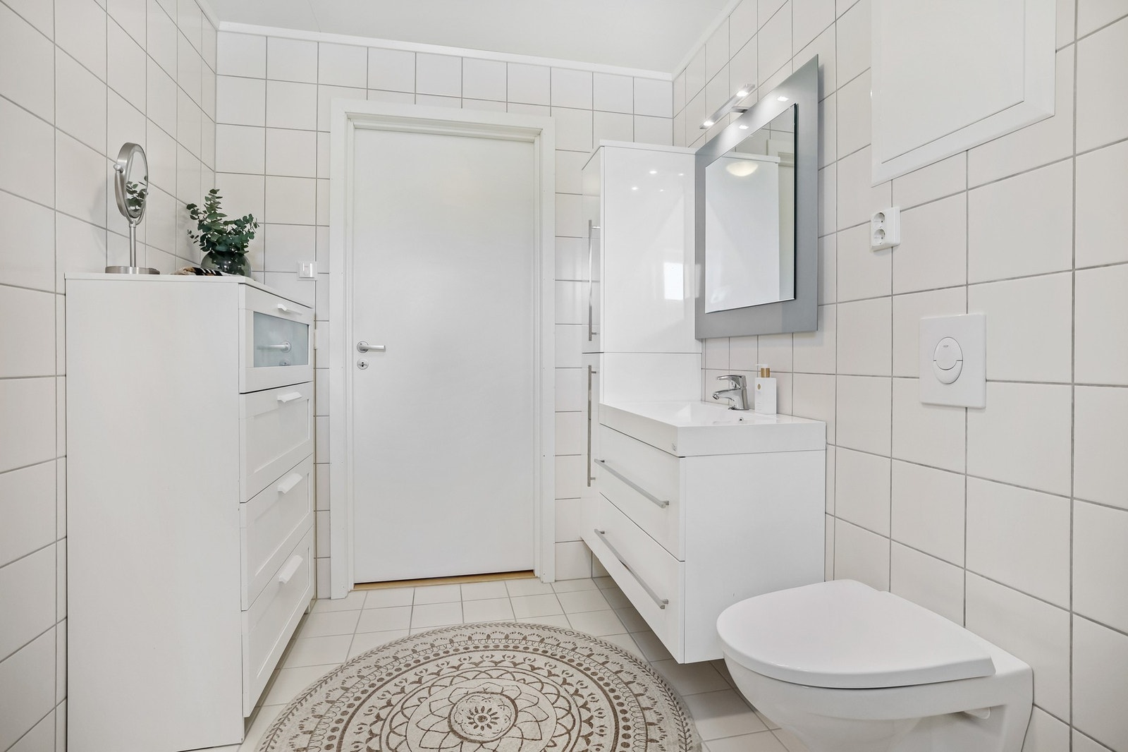 Badet er helfliset med lyse fliser på både gulv og vegger, og har en moderne innredning med alt en trenger Galleribilde