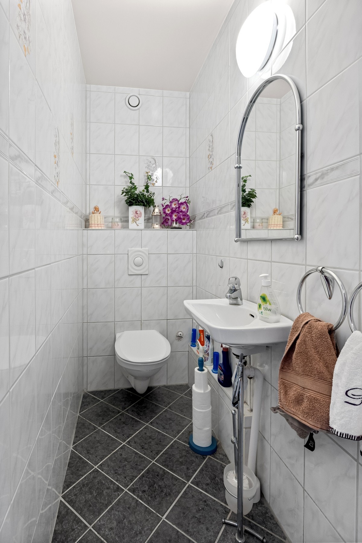 Flislagt toalettrom med servant, blandebatteri og vegghengt toalett. Galleribilde