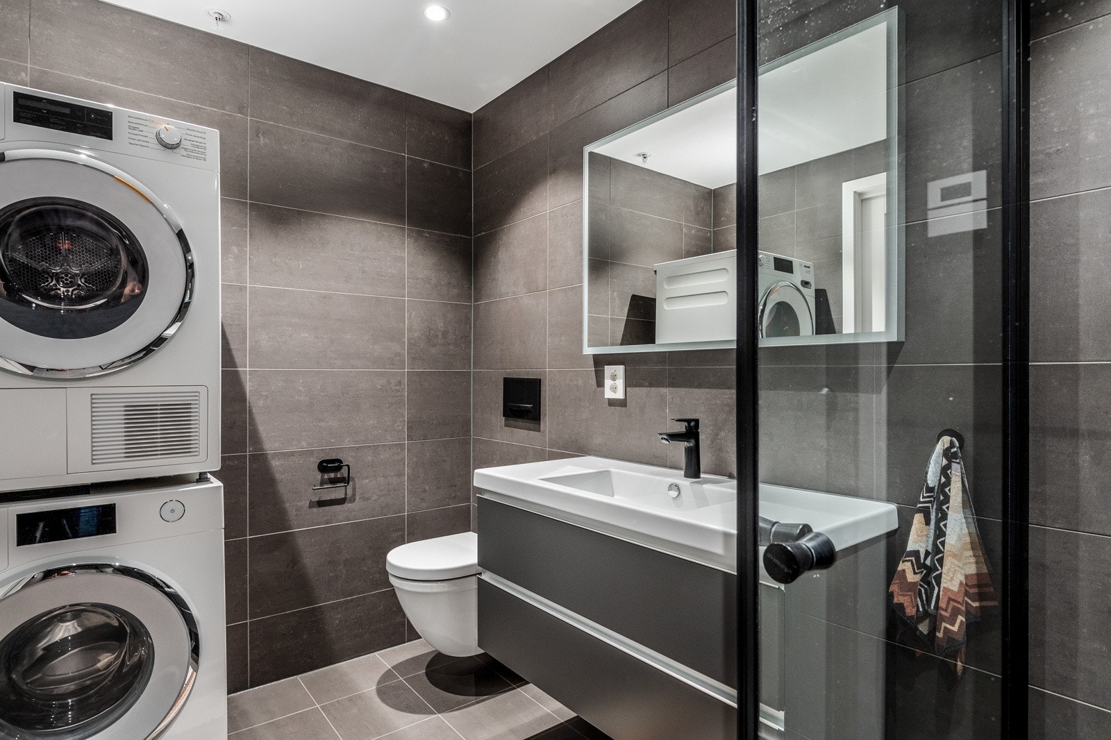 Bad 1 med inngang fra soverommet har innredning med nedfelt servant, veggfestet toalett og dusjnisje Galleribilde