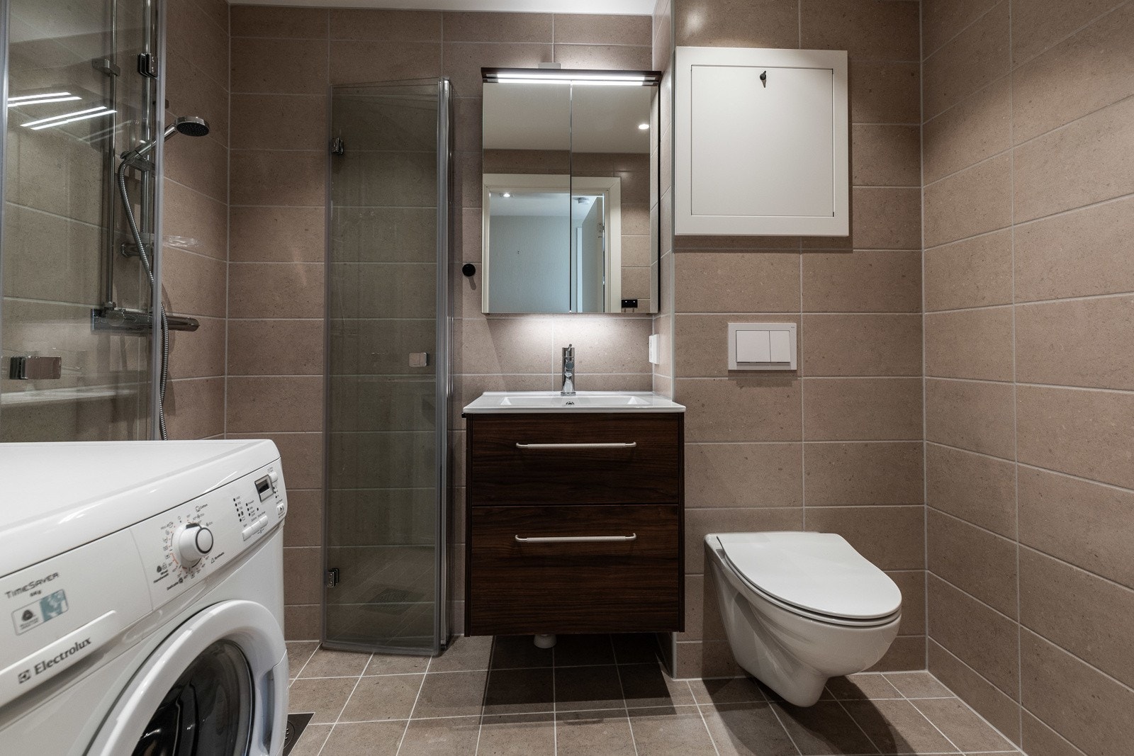 På badet er det vegghengt toalett, opplegg for vaskemaskin og et dusjhjørne med innfellbare vegger. Galleribilde