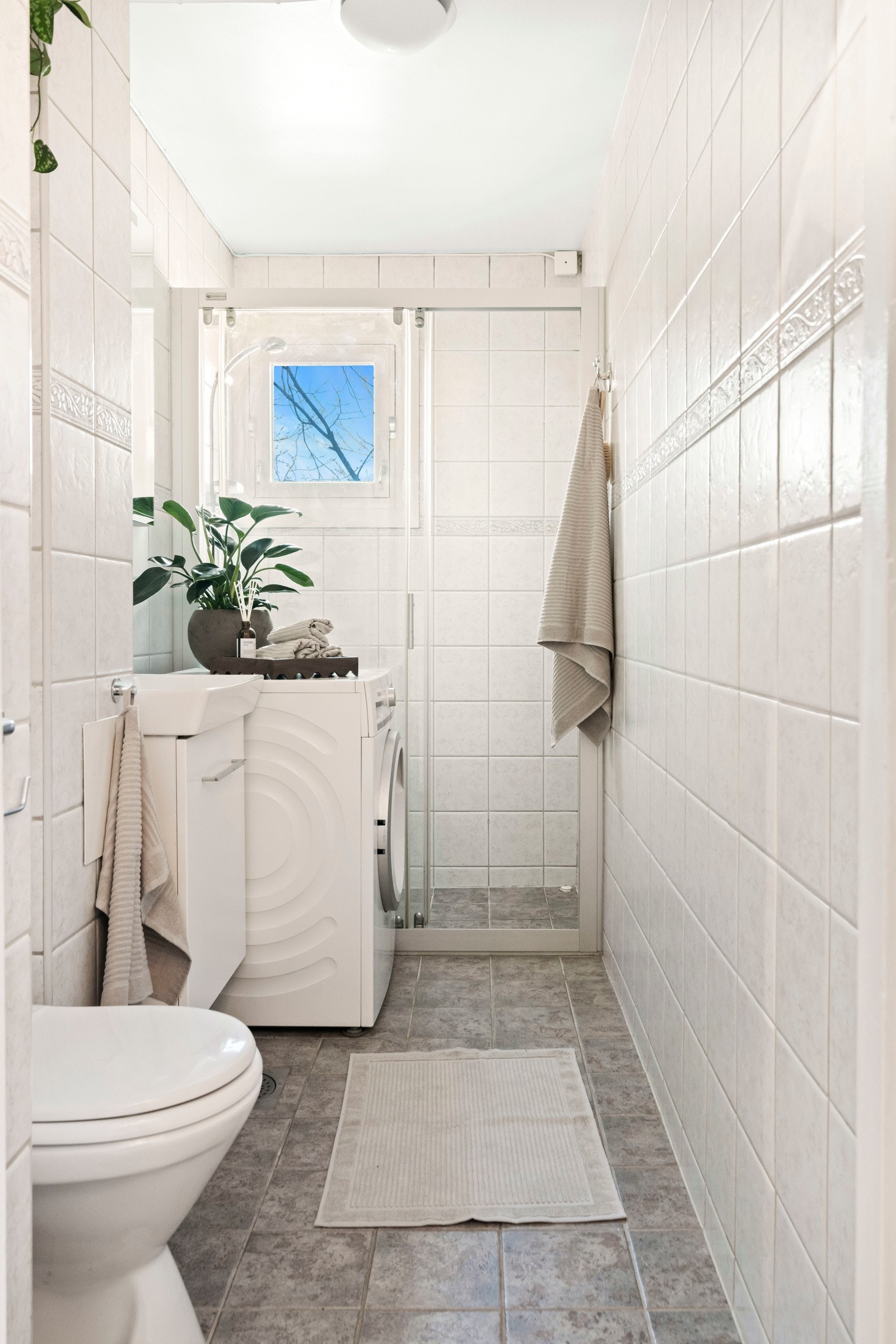 Badet har et vindu for naturlig lys, varmekabler i gulv og er innredet med et servantskap med speilskap, toalett og dusjsone. Opplegg for vaskemaskin. Galleribilde