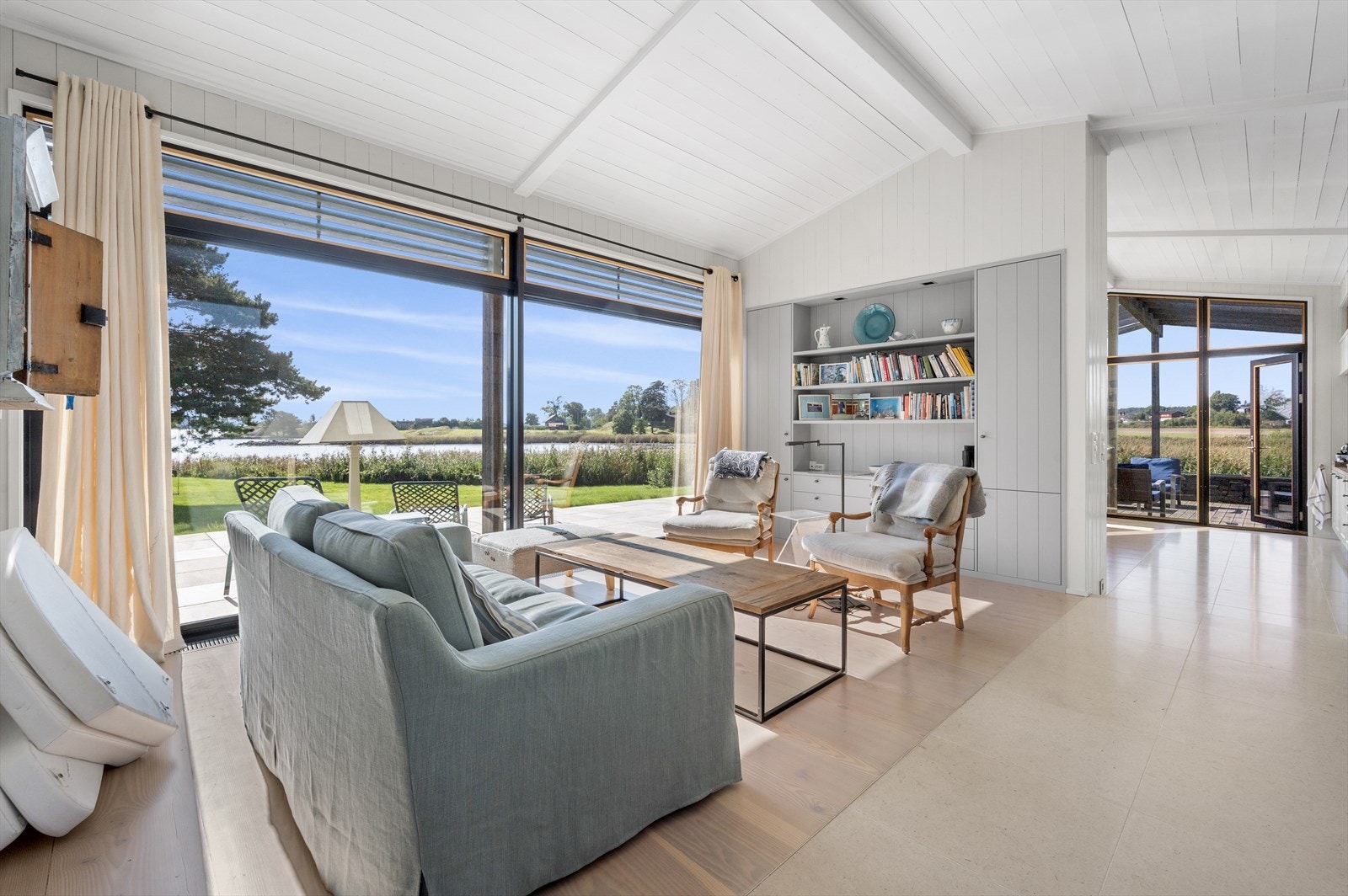 Stuen ligger tilknyttet spisekjøkkenet, der en vegg med plassbygde skap, skjenk og hyller fungerer som delevegg. Galleribilde