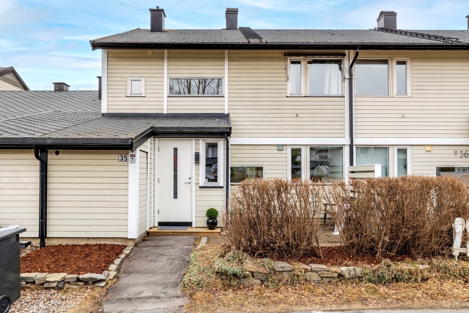 Rekkehusets inngangsparti ligger østvendt med asfaltert adkomst og en liten tram foran inngangsdøren. Her er det også inngang til en praktisk utebod på ca. 4 kvm. Ved siden av er det hellelagt uteplass med levegg mot nabo og skjermende hekk mot veien. Galleribilde