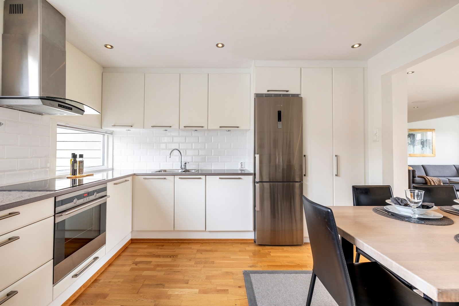 Kjøkkenet har et lys og stilren innredning plassert i romslig L-form, i åpen løsning til stuen. Innredningen har takoppforede skap, lyse, glatte fronter og benkeplate i grå laminat med nedfelt vaskekum. Vinduer over endebenken og dimmbare LED downlights. Galleribilde