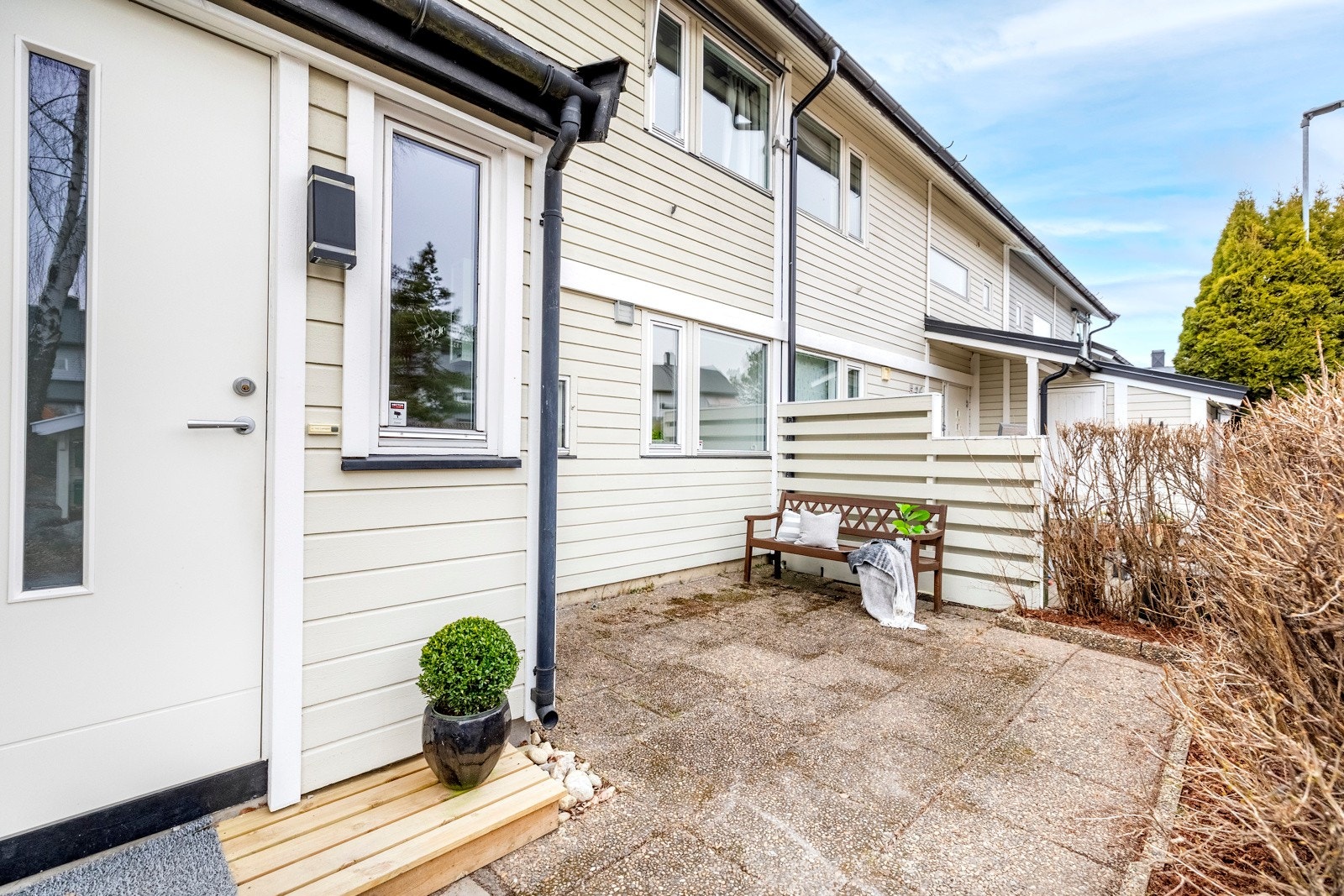 Rekkehusets inngangsparti ligger østvendt med asfaltert adkomst og en liten tram foran inngangsdøren. Her er det også inngang til en praktisk utebod på ca. 4 kvm. Ved siden av er det hellelagt uteplass med levegg mot nabo og skjermende hekk mot veien. Galleribilde