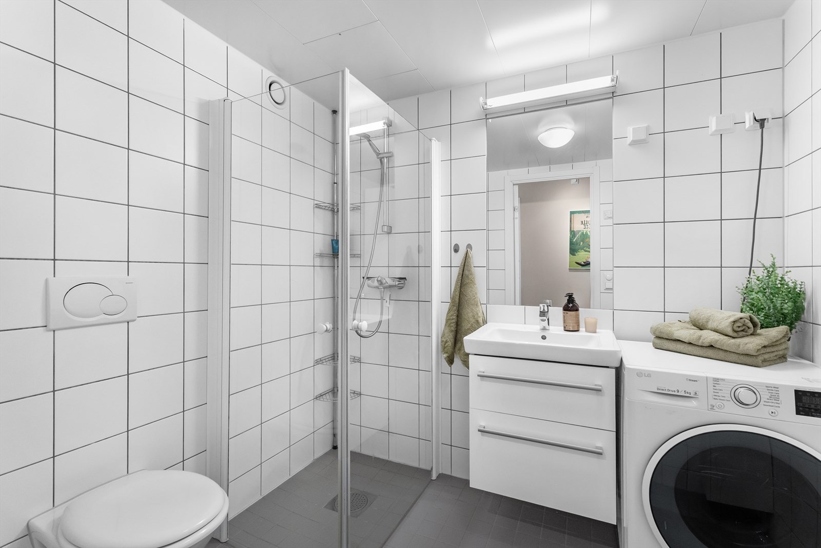 Baderomsinnredningen består av servantskap med skuffeseksjoner, dusjsone, toalett og opplegg for vaskemaskin Galleribilde