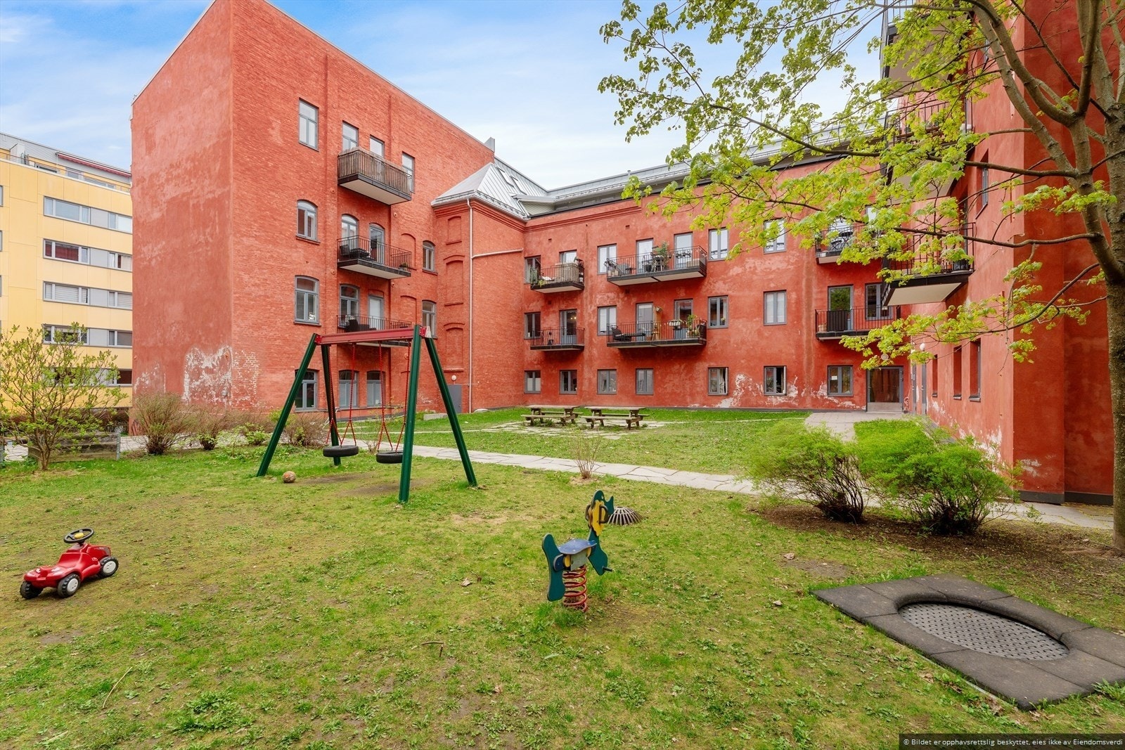 Bakgården er pent opparbeidet med sittegrupper, lekeplass og beplantning. Galleribilde