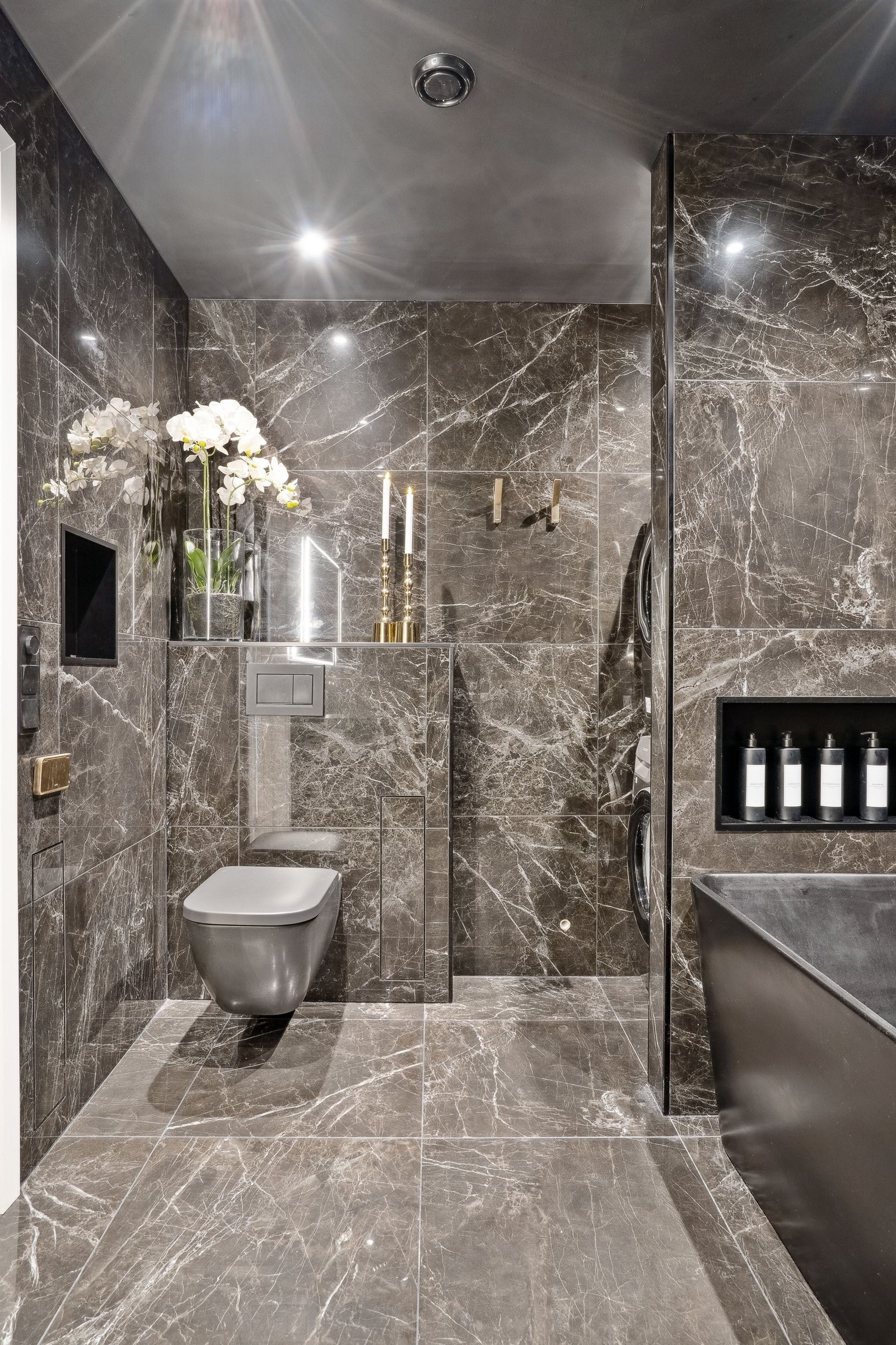 Vegg skjuler vaskemaskin og tørketrommel fra resten av badet. Galleribilde