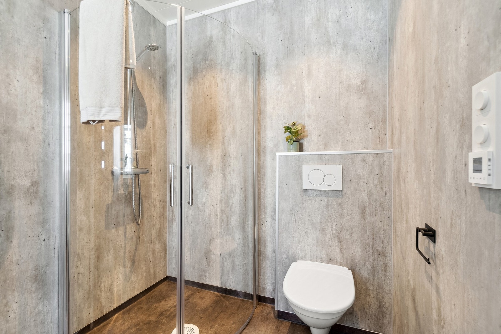 Dette badet har en frittstående dusjsone med glassdører, frittstående toalett og servant innfelt i baderomsinnredning med skuffer. Galleribilde