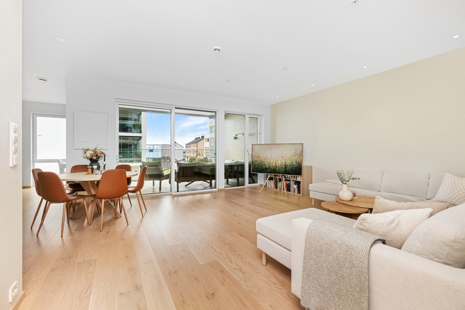 En stor og lys stue med store vindusflater ut mot balkongen og det pene fellesområdet. Galleribilde