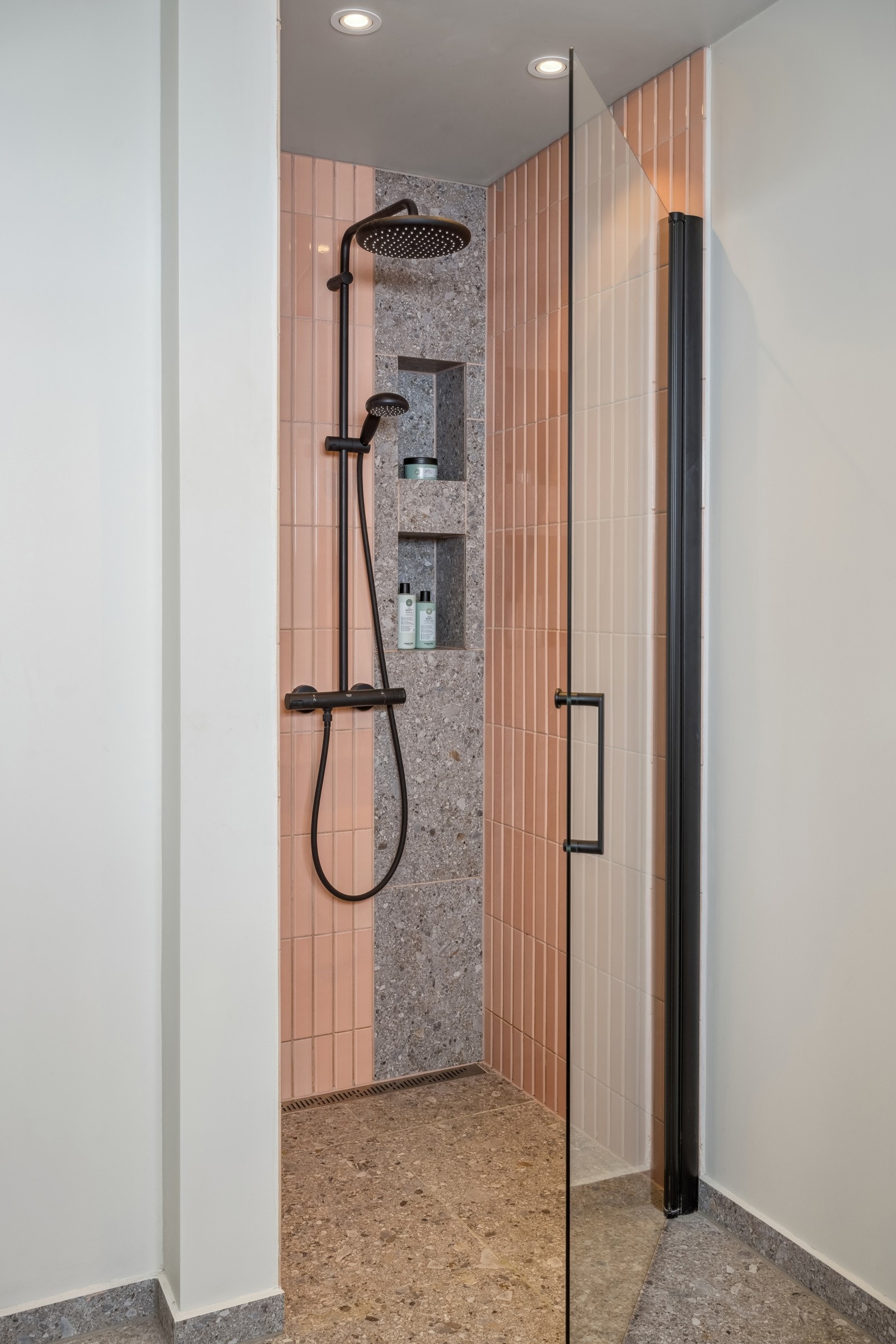 Innerst i rommet er det lekker dusjnisje med fargerike veggfliser, innmurt hylle for såper, slukrenne, og regnfalldusj. Galleribilde