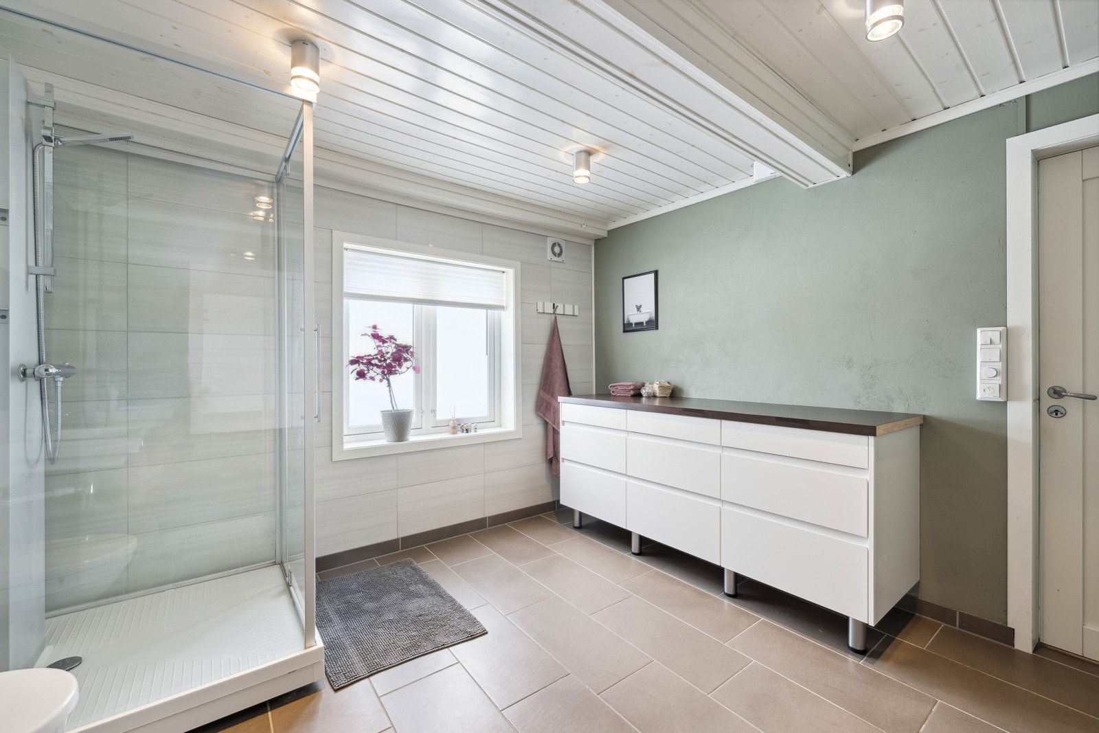 Et stort og innbydende bad med flislagt gulv med varmekabler og delvis flislagte vegger. Galleribilde