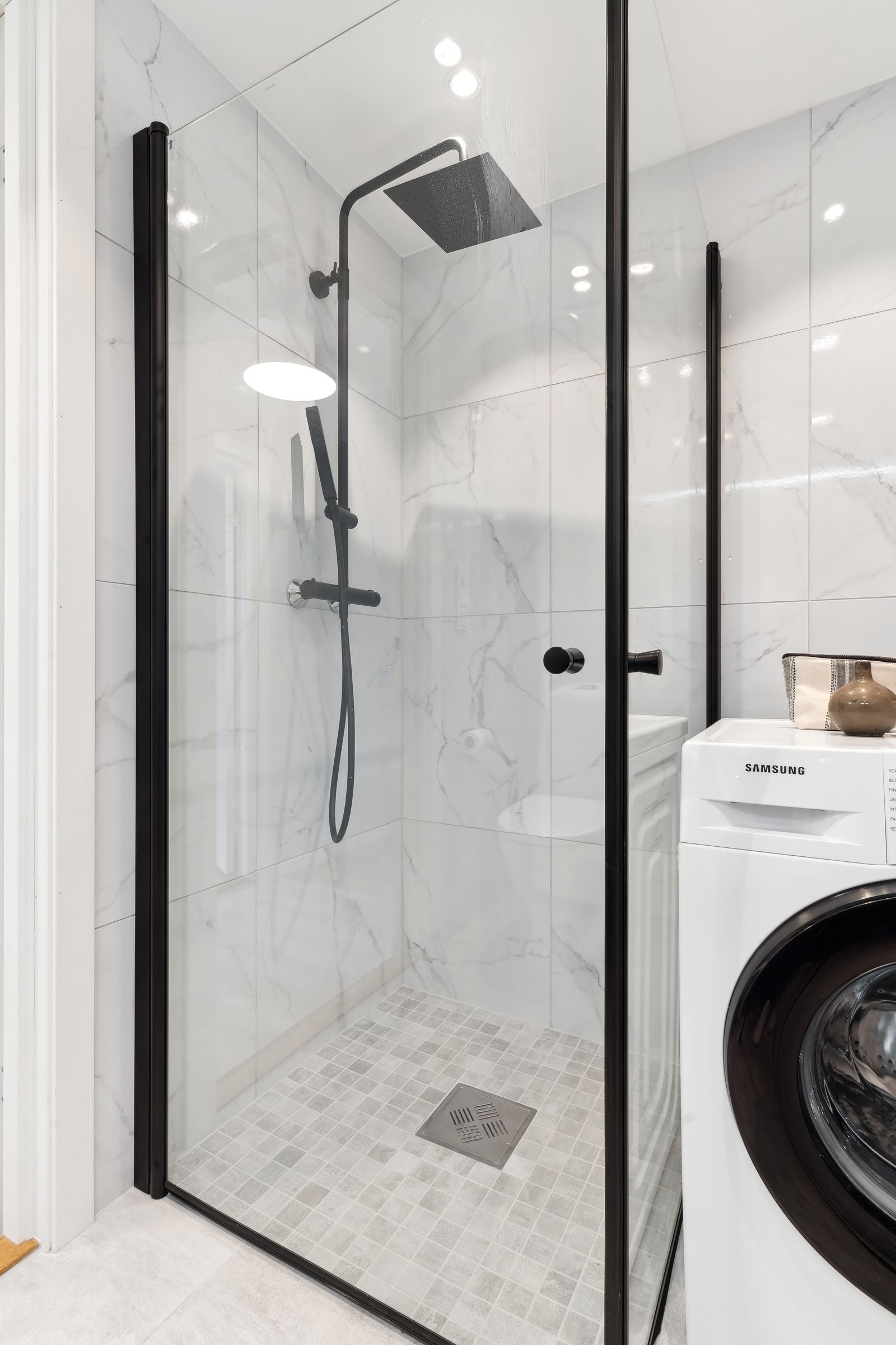 Praktisk og elegant bad med flislagt, nedfelt dusjsone og tidsriktige materialvalg. Galleribilde