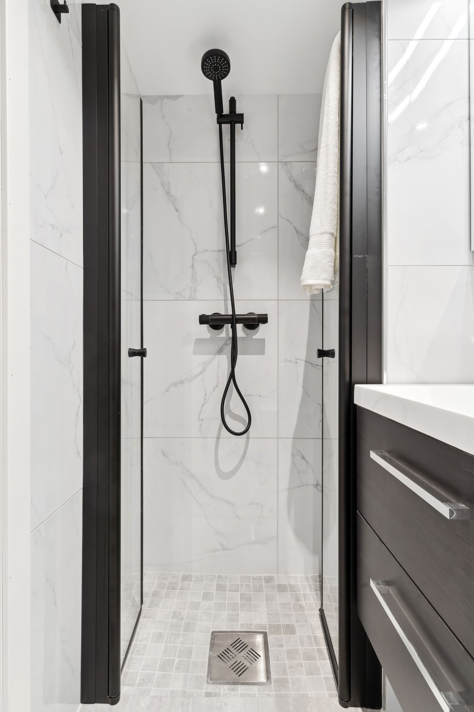 Dusj med innfellbare dører, nedfelt gulv og veggmontert armatur – perfekt for optimal plassutnyttelse. Galleribilde