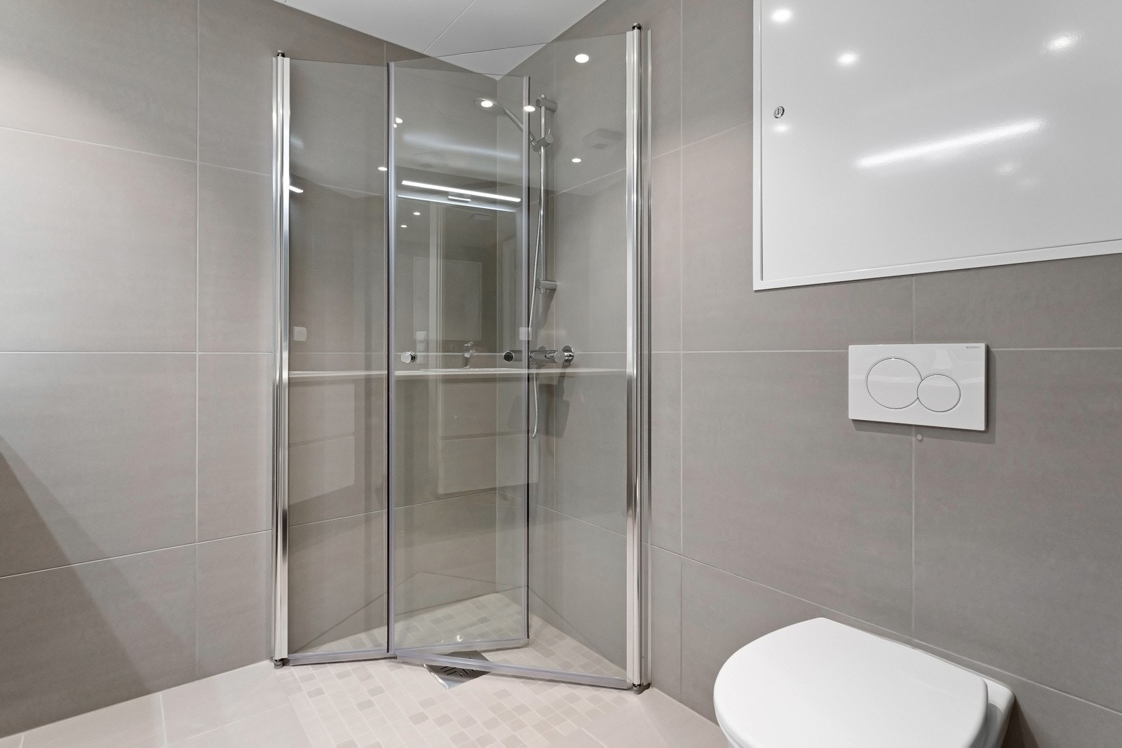 Romslig dusjnisje med innadslående dører. Galleribilde