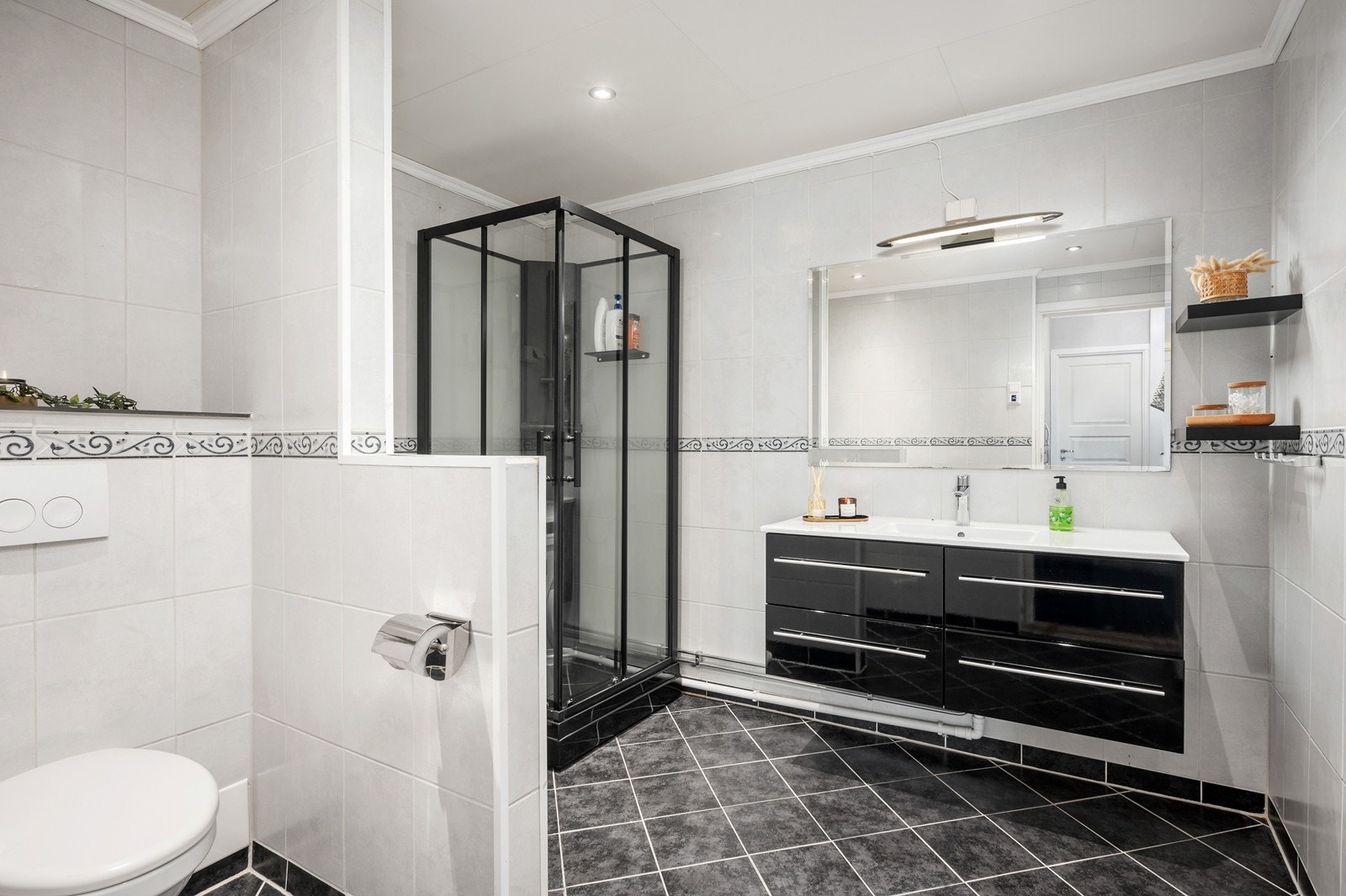 Badet har flislagte gulv og vegger, samt nedsenket himling med folierte plater og downlights Galleribilde