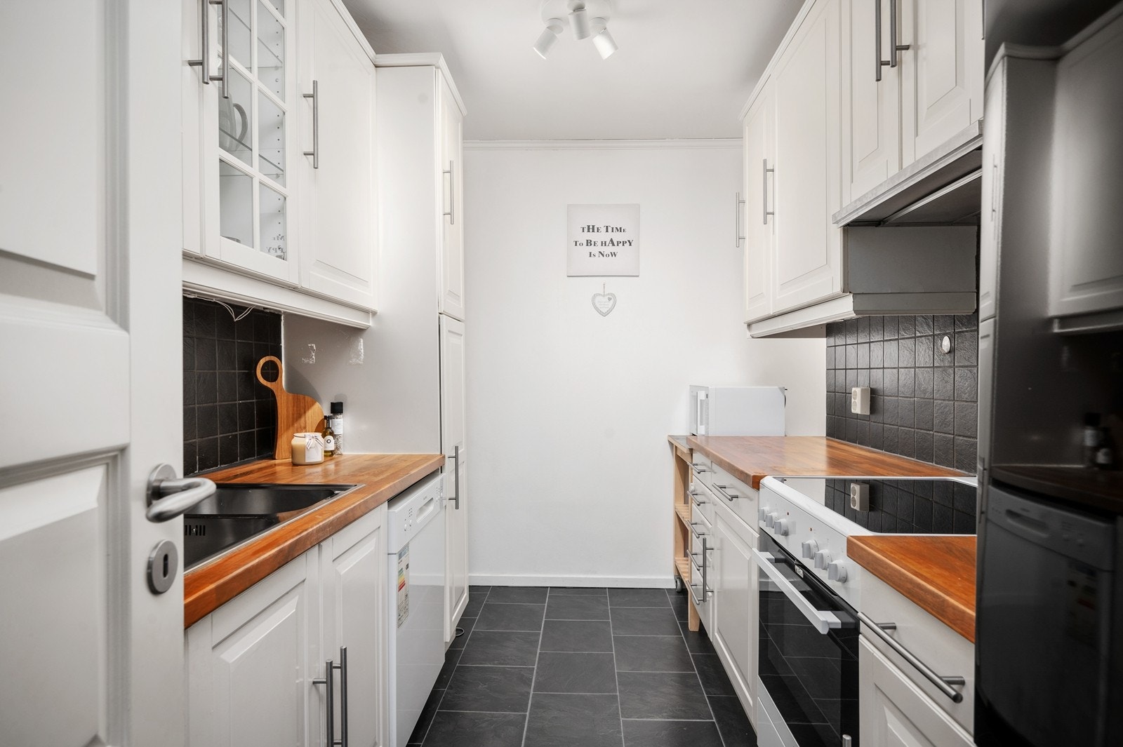 Kjøkkenet har profilerte fronter, benkeplate av laminat og fliser på vegg mellom benk og overskap. Galleribilde