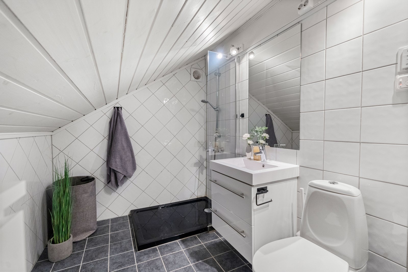 Fra loftstuen er det inngang til et flislagt baderom innredet med dusjkar, gulvstående klosett samt servant med benkeskap. Galleribilde