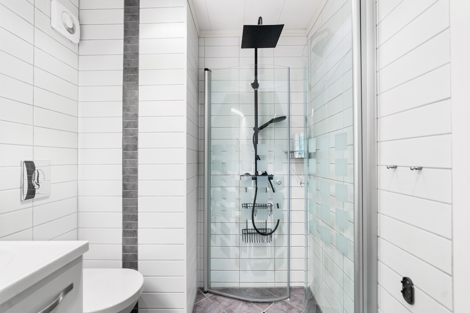 Rommet er utstyrt med dusj med glassdører, veggfestet klosett samt servant med benkeskap. Over servanten er det satt opp overskap med speilfronter. Galleribilde