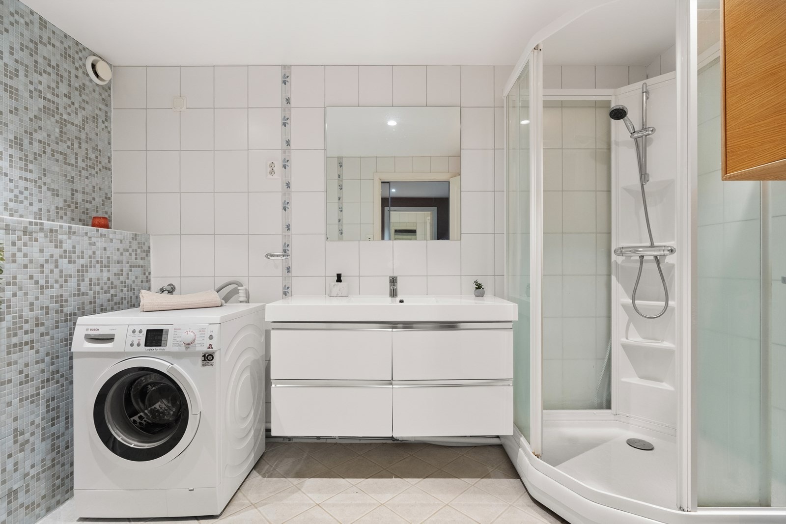 Badet har lyse fliser og gulvvarme og er utstyrt med downlights Galleribilde