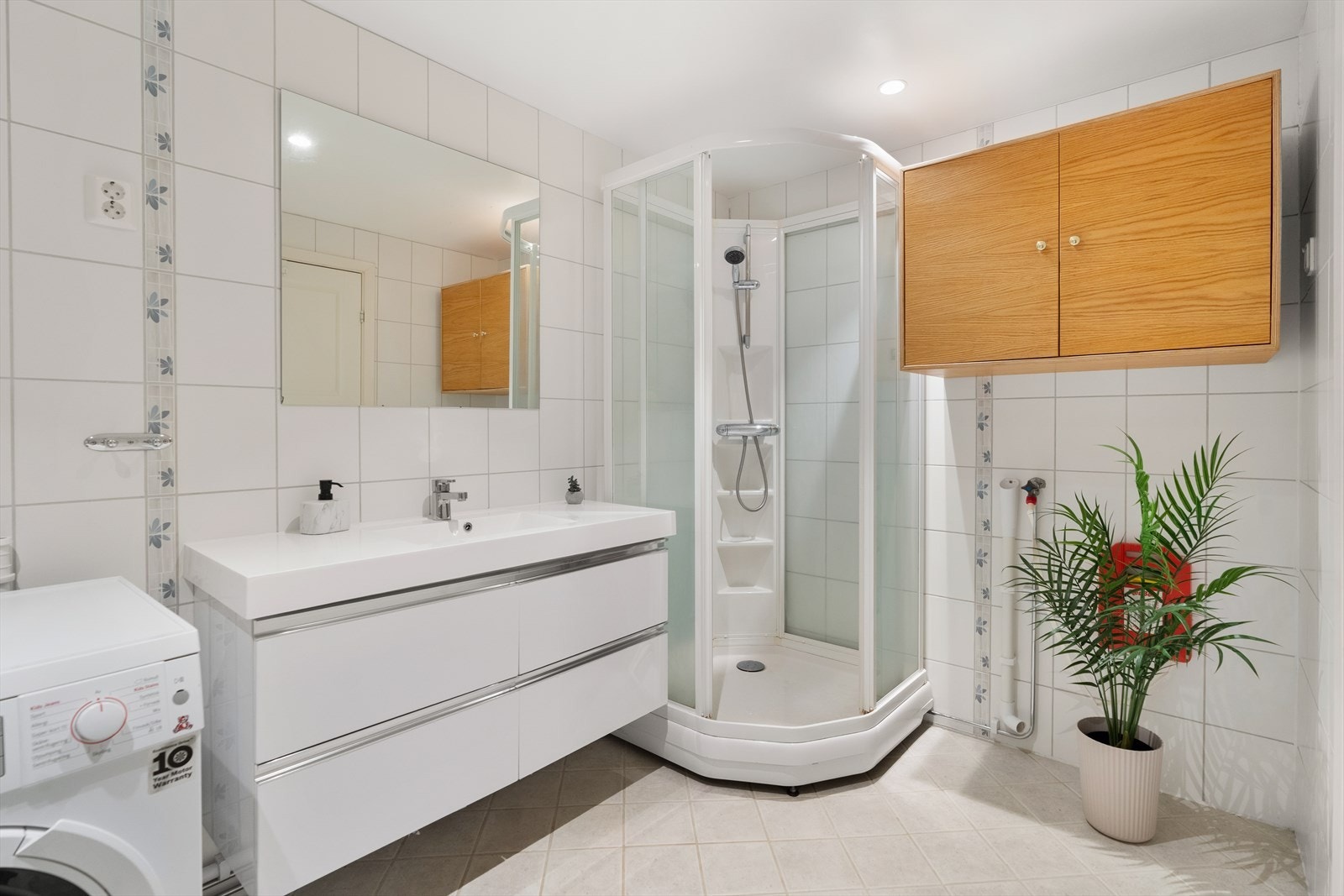 Badet har veggfestet toalett, dusjhjørne og opplegg for vaskemaskin. Galleribilde