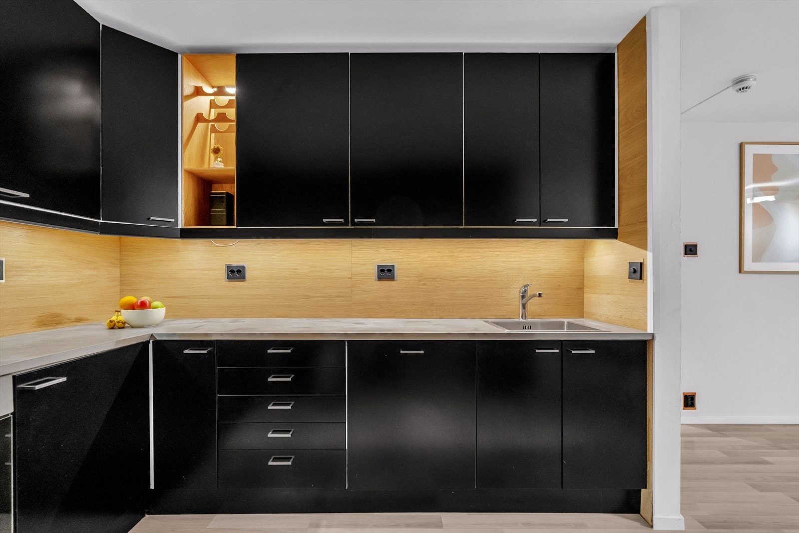 Skapene har sorte glatte fronter, og det er satt inn laminat benkeplate med vask. Galleribilde